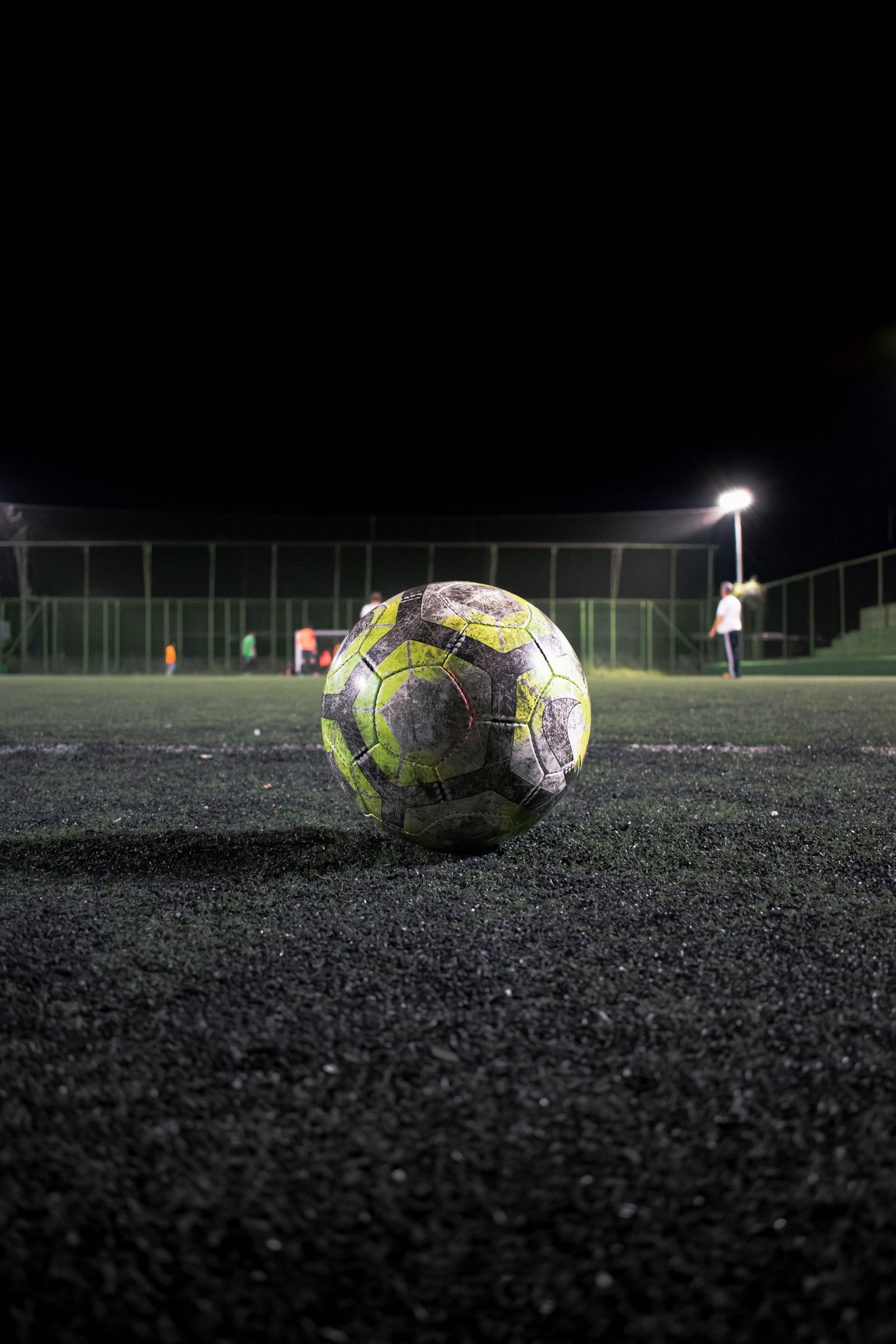Soccer ball on a pitch under stadium floodlights